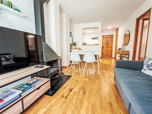 A modern living room with a flat-screen TV, a fireplace, a dining area with a table and chairs, and a sofa. - Chimenea y modernidad-Dellui 3 by Interhome (Taüll)
