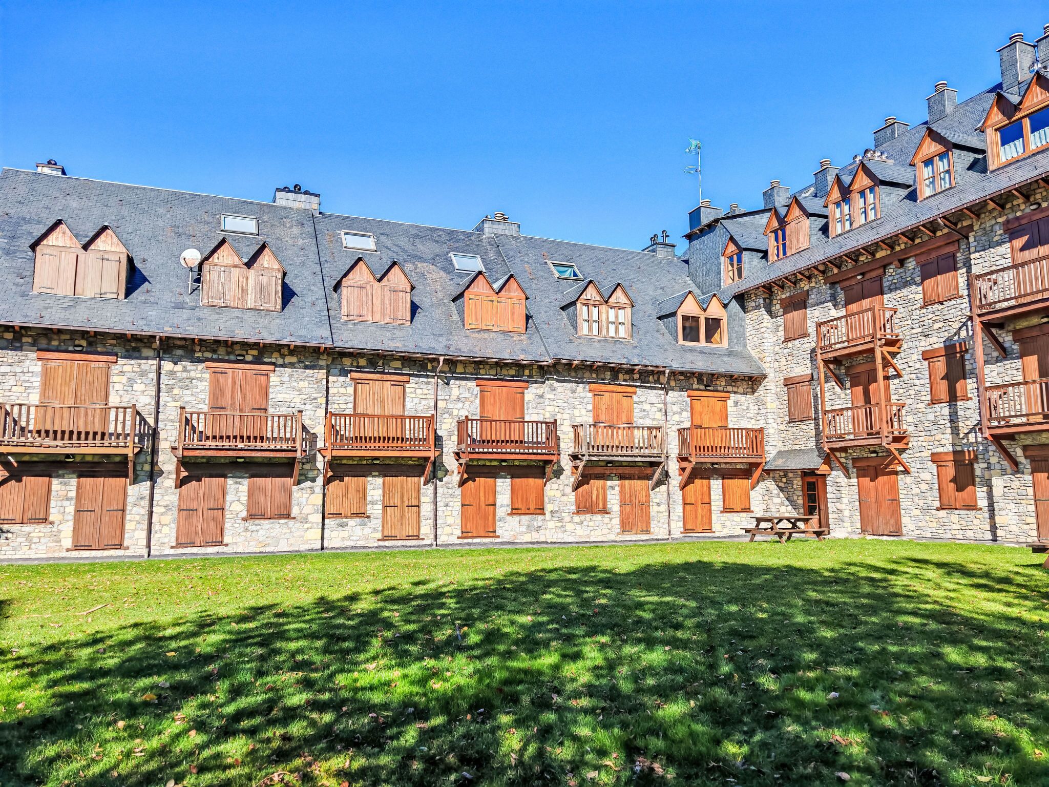 Ein Steinhaus mit mehreren Balkonen und einem grünen Innenhof.