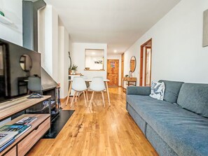 A modern living room with a sofa, TV, wooden floor, and a dining area with chairs and a table. - Chimenea y modernidad-Dellui 3 by Interhome (Taüll)