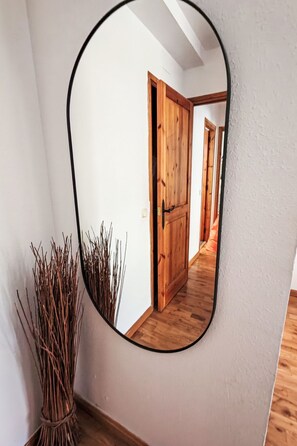 A mirror reflecting a hallway with wooden doors and a plant beside it. - Chimenea y modernidad-Dellui 3 by Interhome (Taüll)
