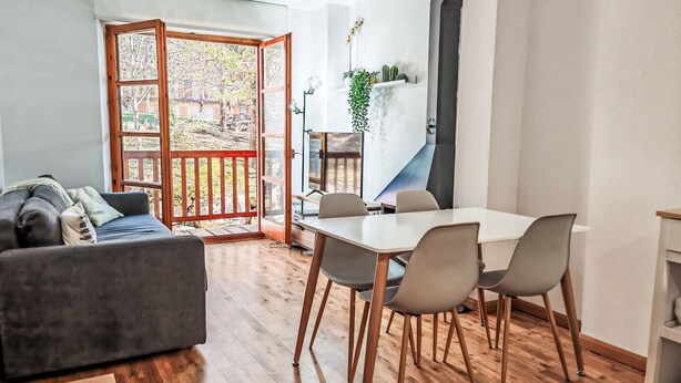 Un espacio habitable moderno con comedor, sofá y vistas a través de un ventanal.
