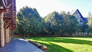 Un sendero pavimentado que conduce a un edificio de piedra con una cerca de madera y árboles al fondo.