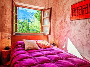 A bedroom with a large window, a bed with a purple bedspread, and a red artwork on the wall. - Apartamento - Puig Falcó 3 by Interhome (Taüll)
