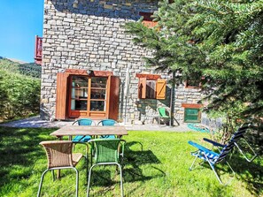 A stone building with a wooden door, windows, and a table with chairs in front. - Apartamento - Puig Falcó 3 by Interhome (Taüll)