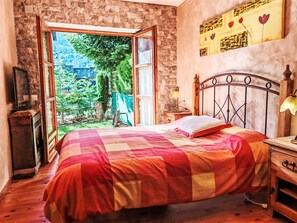 Ein Schlafzimmer mit Bett, Fernseher und Blick auf Grünfläche.