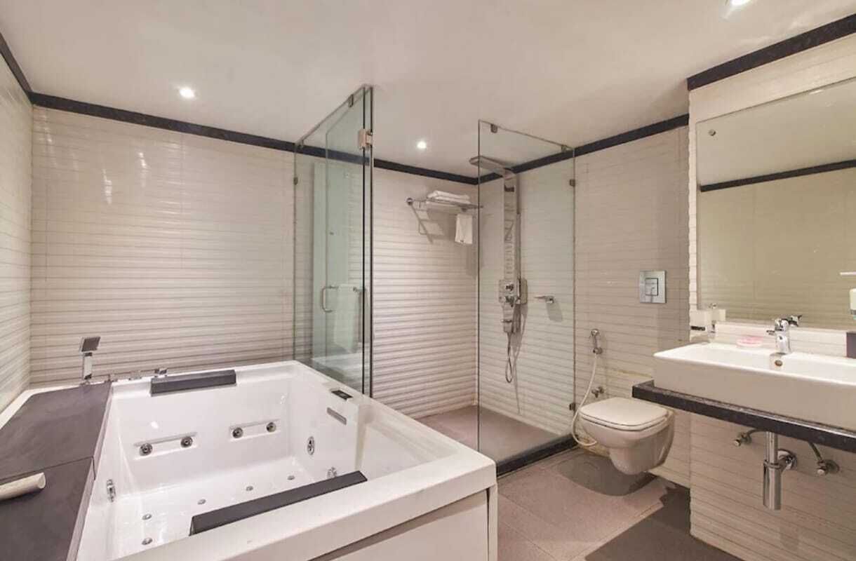 A modern bathroom with a glass-enclosed shower, a separate toilet, and a large bathtub.