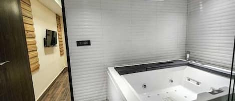 Ein modernes Badezimmer mit einer großen Badewanne, Holzboden und Fliesenwand.