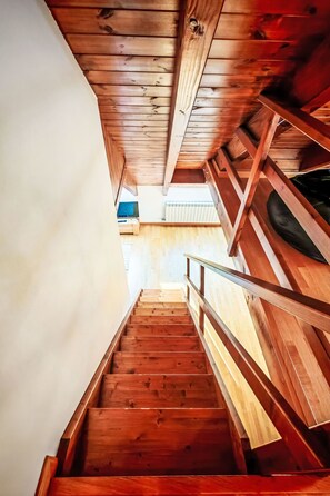 Eine Holztreppe mit Metallgeländer, die zu einer oberen Etage führt.
