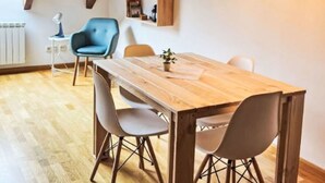 A dining area with a wooden table and chairs, pendant lighting, and built-in shelves. - Dúplex Luminoso - Erta 12 by Interhome (Taüll)