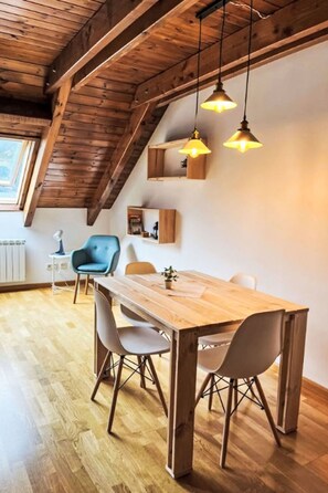 Ein Essbereich mit Holztisch und -stühlen, Pendelleuchten und integrierten Regalen.