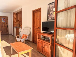 Ein Wohnzimmer mit einem Holzkabinett, einem Fernseher, einem Sessel und einem Tisch.
