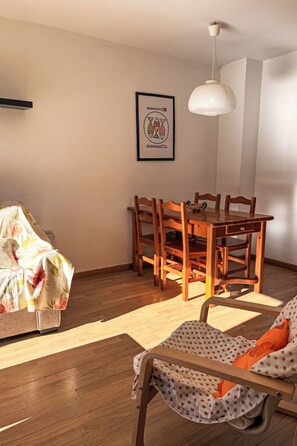 Ein Essbereich mit einem Holztisch, Stühlen, einer Pendelleuchte und einem gerahmten Bild an der Wand.