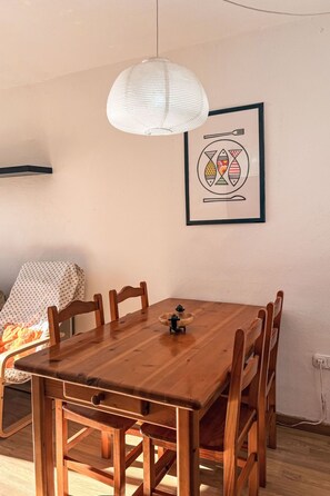 Ein Holztisch mit Stühlen, eine Hängelampe und ein gerahmtes Bild an der Wand.