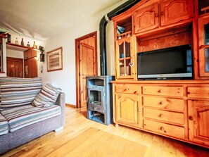 Ein gemütliches Wohnzimmer mit einer Couch, Holzausbau, einem Kamin und einem Fernseher.