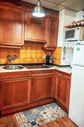 A kitchen with wooden cabinets, a microwave, a coffee maker, and a refrigerator. - Escapad para parejas - Justal 2 by Interhome (Taüll)