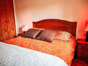 A bed with a patterned bedspread, two pillows, a nightstand with a lamp, and a wooden wardrobe. - Escapad para parejas - Justal 2 by Interhome (Taüll)