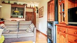 A cozy living room with a striped sofa, wooden cabinets, a television, and a fireplace. - Escapad para parejas - Justal 2 by Interhome (Taüll)