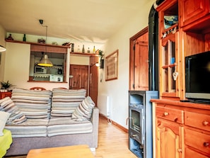 Ein gemütliches Wohnzimmer mit einem gestreiften Sofa, Holzschränken, einem Fernseher und einem Kamin.
