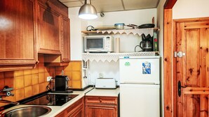 A compact kitchen with wooden cabinets, a microwave, a toaster, and a coffee maker. - Escapad para parejas - Justal 2 by Interhome (Taüll)