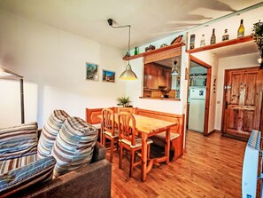 Ein Essbereich mit Holztisch und Stühlen, einer hängenden Pendelleuchte und einer Küche im Hintergrund.