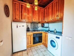 A compact kitchen with wooden cabinets, a built-in microwave, a washing machine, and a refrigerator. - Dúplex de Aigüestort -Falcó 6 by Interhome (Taüll)