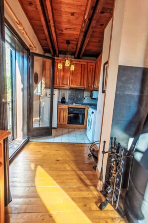 Interior em madeira com cozinha, incluindo máquina de lavar e área de refeições com mesa e cadeiras.
