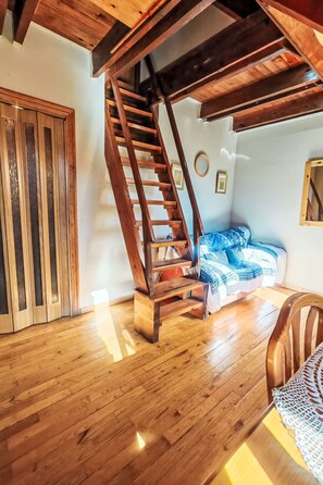 A wooden staircase leading to an upper level, a blue patterned sofa, and a wooden floor. - Dúplex de Aigüestort -Falcó 6 by Interhome (Taüll)