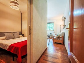 Ein Hotelzimmer mit Bett, roter Decke, Holzboden, Fenster und Stuhl.