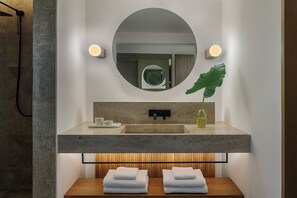 Ein modernes Badezimmer mit großem Spiegel, Waschbecken und Holzwaschtisch.