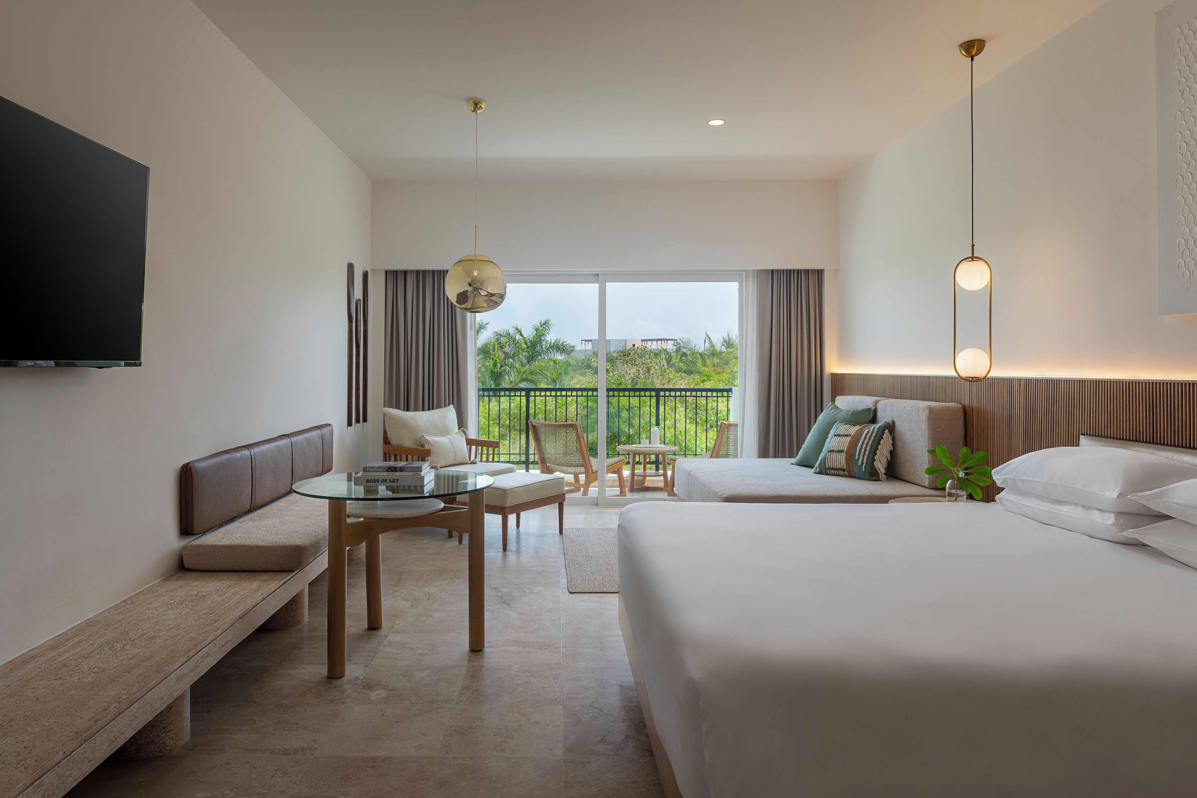 Quarto de hotel com cama, sofá, mesa de jantar e televisão.