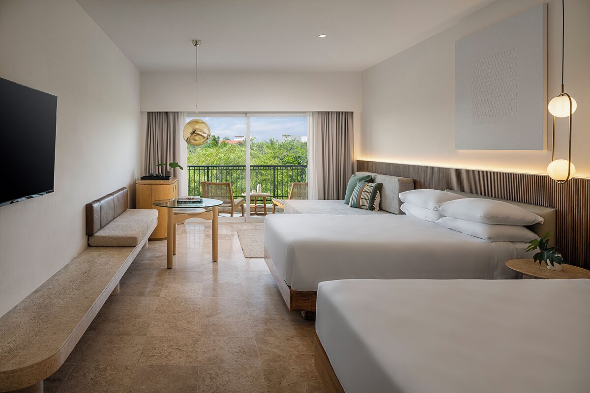 Ein Hotelzimmer mit Bett, einer Couch, einem kleinen Tisch, einem Fernseher und einem Balkon mit Blick.