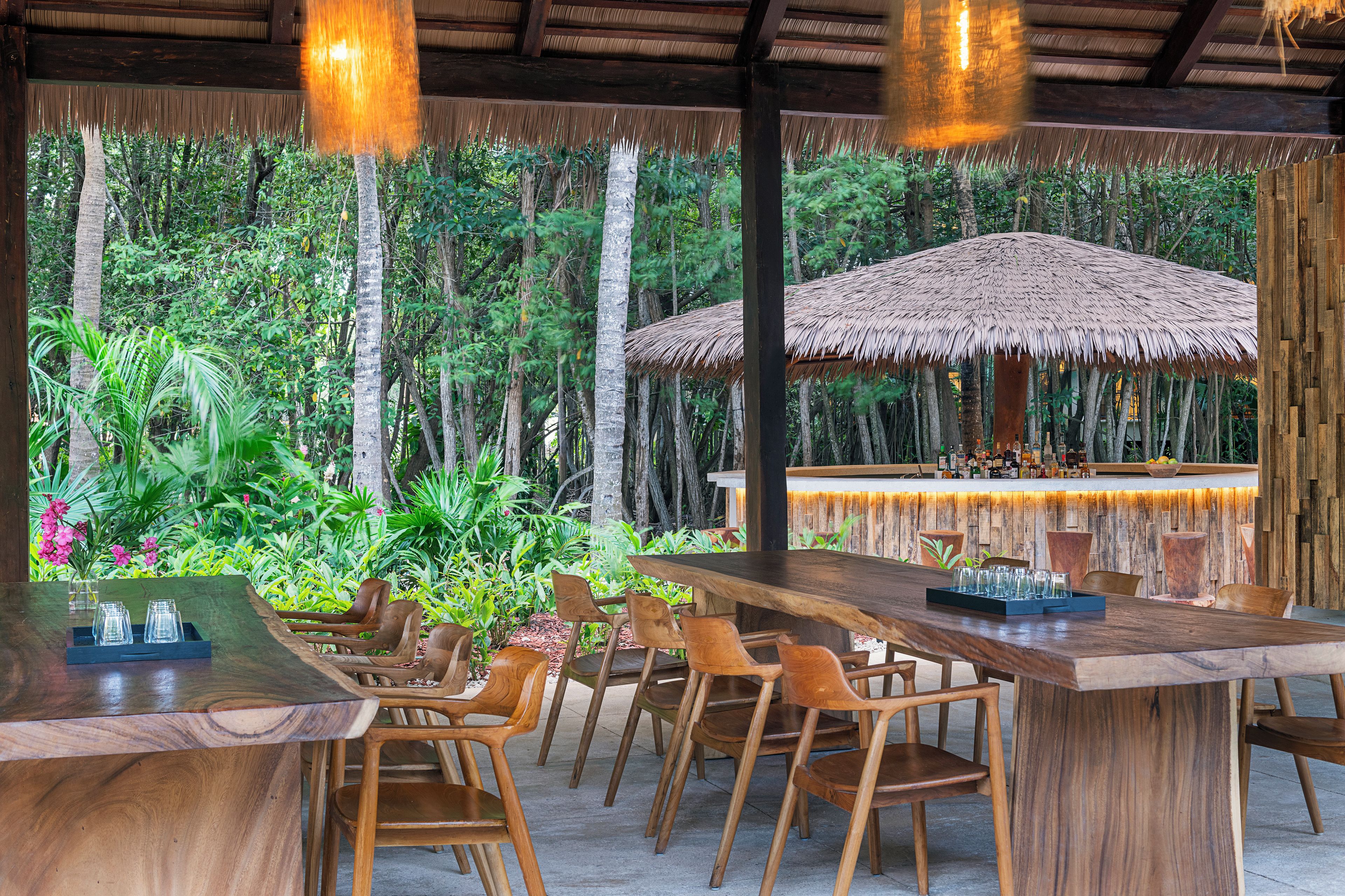 An outdoor dining area with wooden furniture and a thatched roof structure.