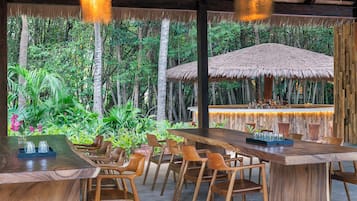 An outdoor dining area with wooden furniture and a thatched roof structure.