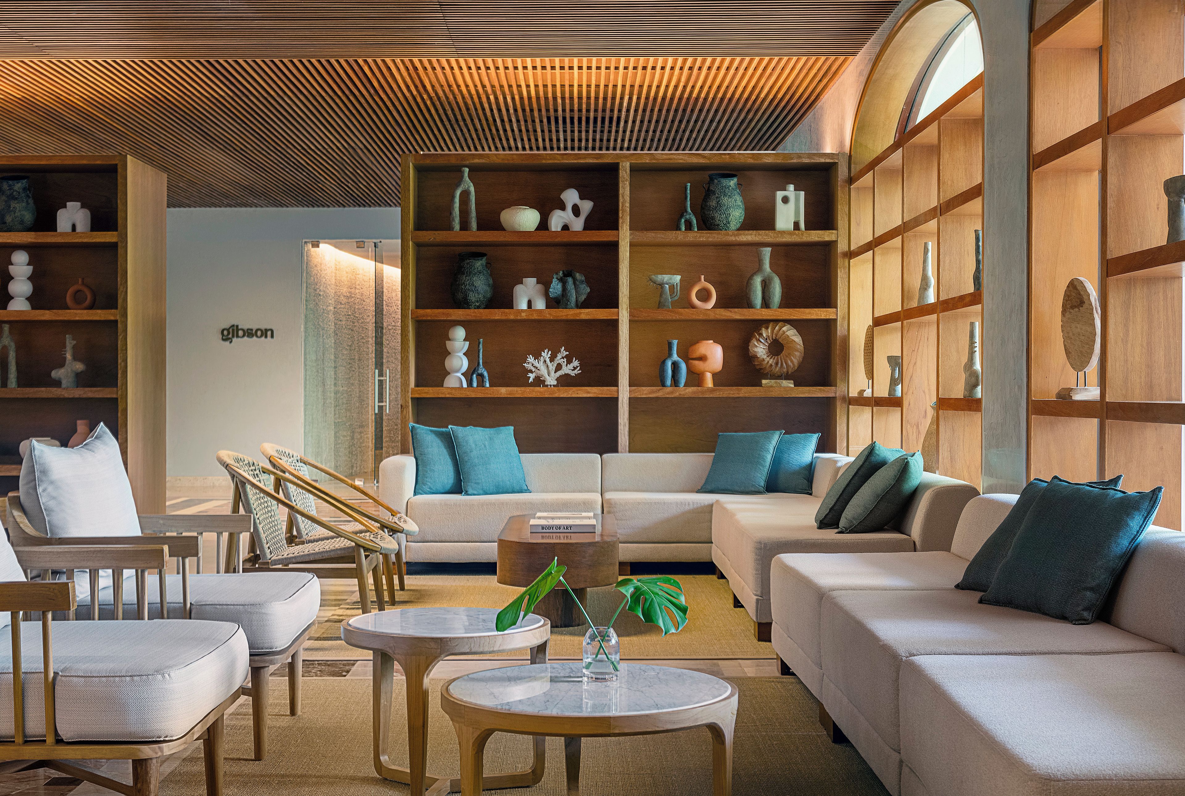 A modern living room with a sofa, chairs, a coffee table, and a bookshelf filled with decorative items.