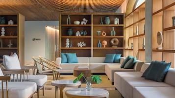 A modern living room with a sofa, chairs, a coffee table, and a bookshelf filled with decorative items.