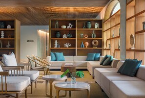 Ein modernes Wohnzimmer mit einer Couch, Sesseln, einem Couchtisch und einem Bücherregal voller Dekoration.