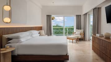Ein modernes Schlafzimmer mit einem großen Bett, Nachttischen, einem Fernseher und Blick auf Grün hinter dem Fenster.