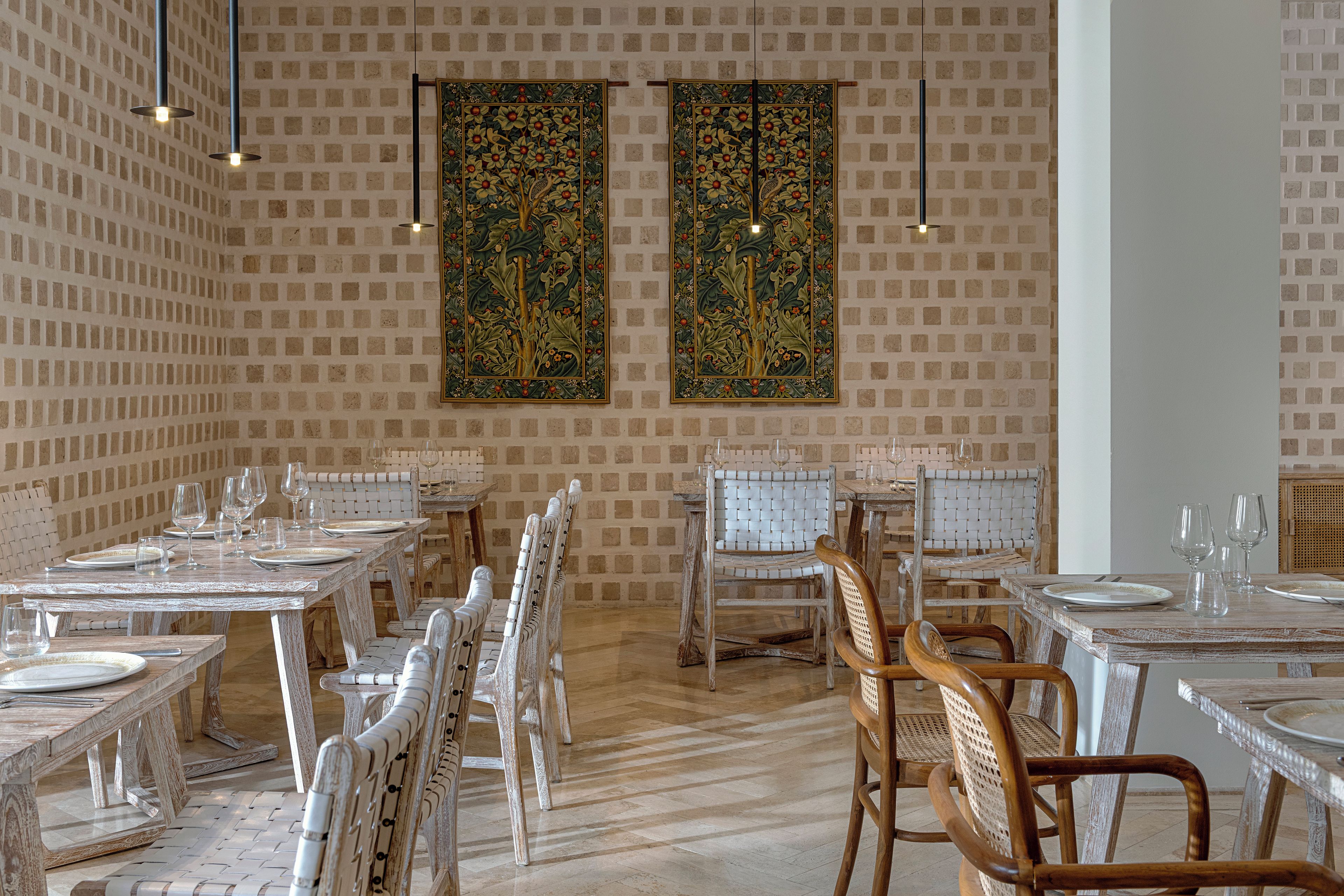 A dining area with multiple tables and chairs, a patterned wall, and hanging decorations.