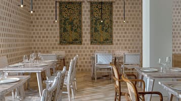 A dining area with multiple tables and chairs, a patterned wall, and hanging decorations.