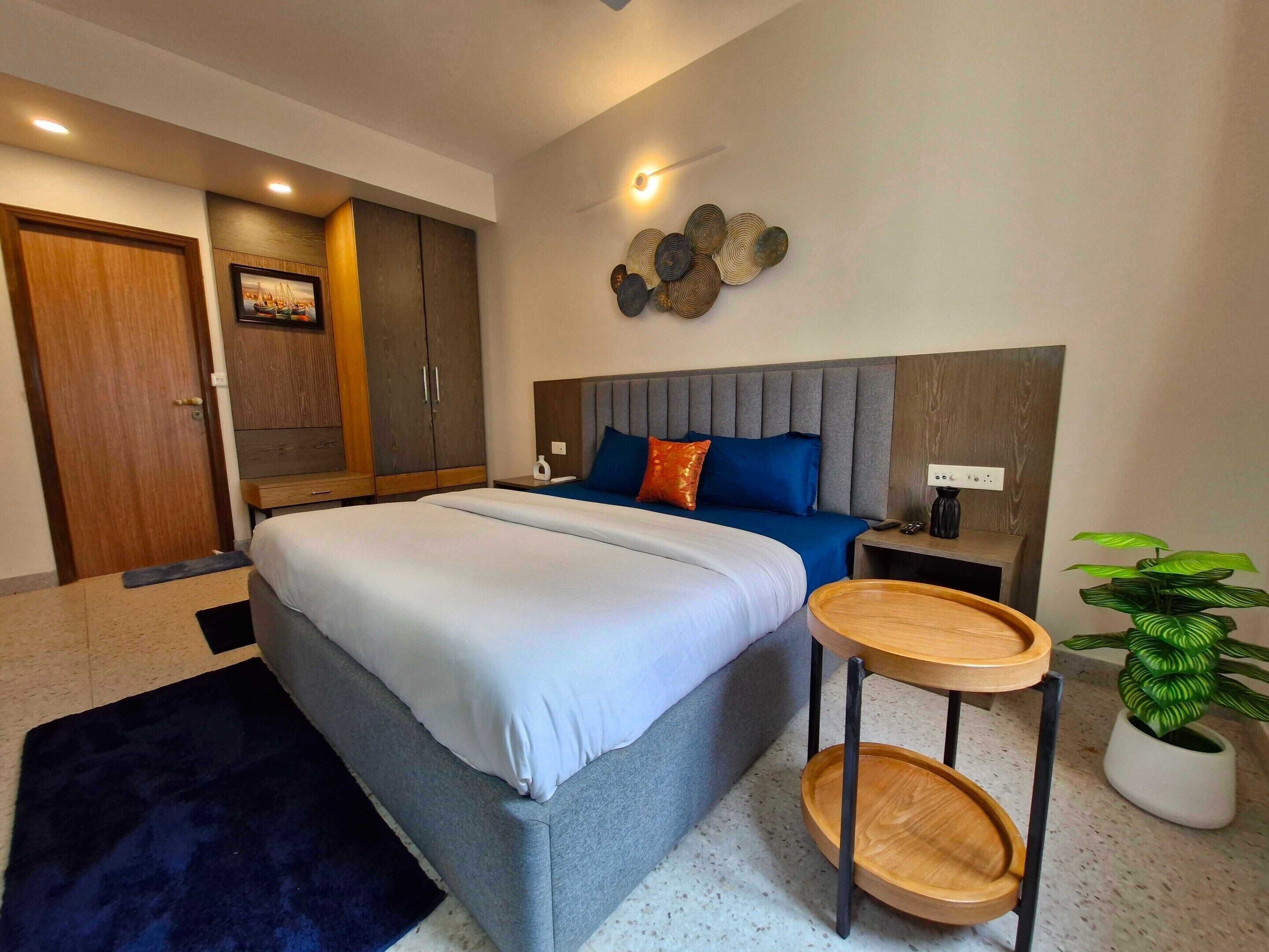 A modern bedroom with a bed, bedside table, and a potted plant.