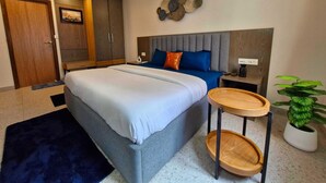 A modern bedroom with a bed, bedside table, and a potted plant. - Classic King Clubhouse Vytilla Kochi (Kanayannur)