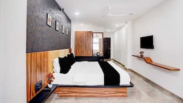 A modern bedroom with a wooden headboard, a flat-screen TV, a bedside table, and a nightstand.