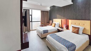 A hotel room with two beds, a flat-screen TV, a ceiling fan, and a large window with curtains. - Classic King Clubhouse Vytilla Kochi (Kanayannur)