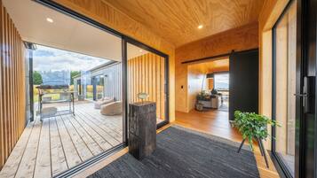 A modern interior with wooden flooring, a black rug, a wooden post, and a potted plant.