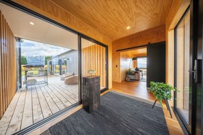 A modern interior with wooden flooring, a black rug, a wooden post, and a potted plant.