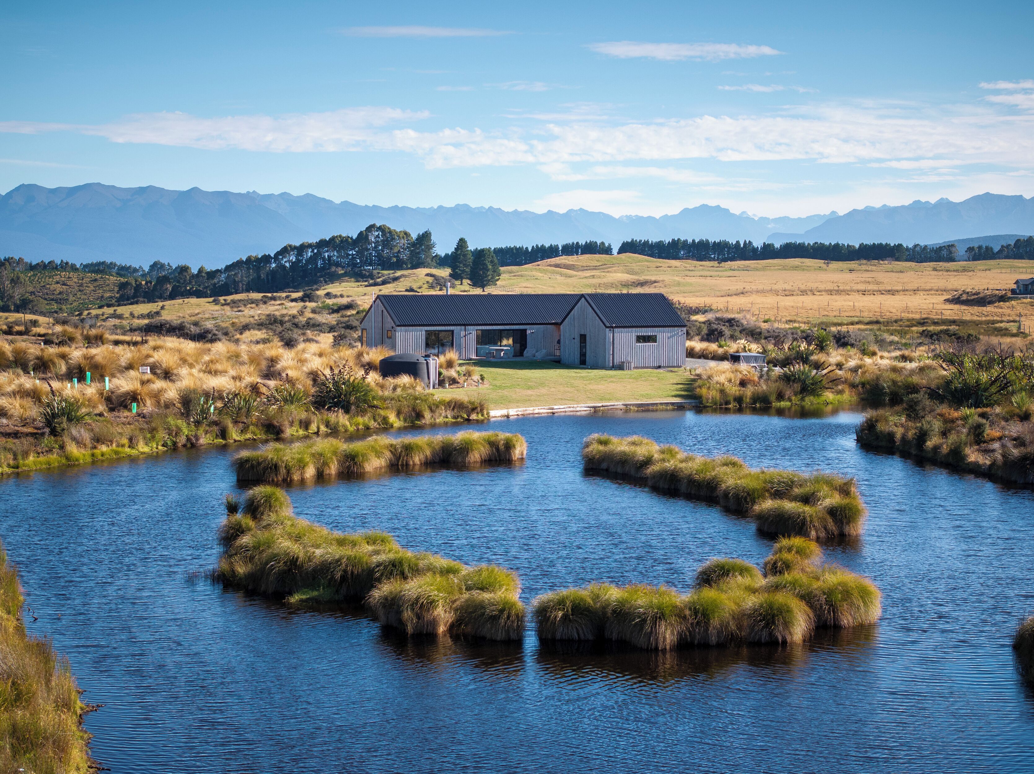 A lakeside property with a house, a dock, and a view of distant mountains.