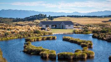 A lakeside property with a house, a dock, and a view of distant mountains.