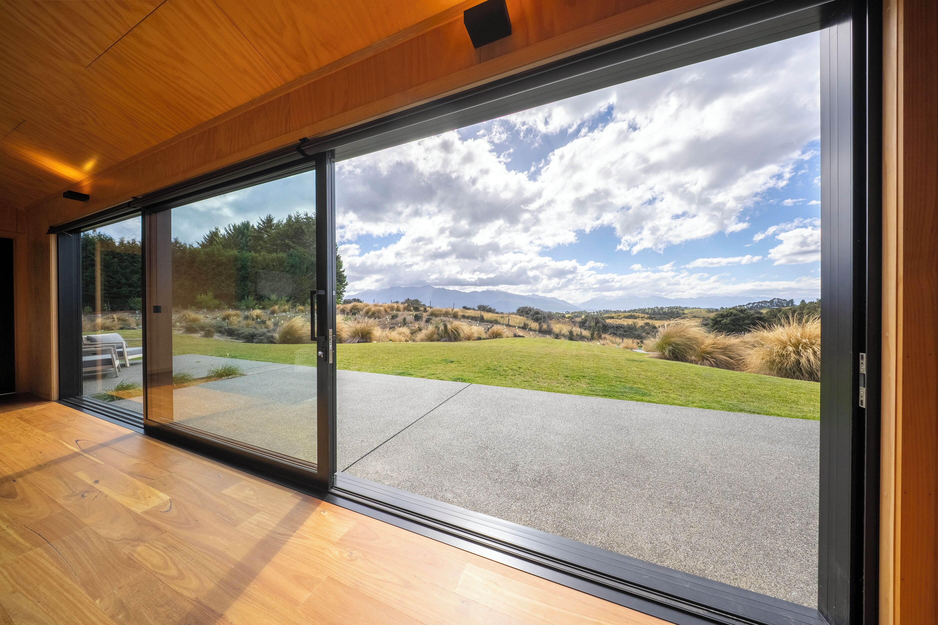 A modern interior with large sliding glass doors leading to a landscaped outdoor area.