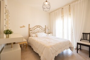 Een slaapkamer met een bed, nachtkastje, lamp, stoel en een spiegel met verlichting.