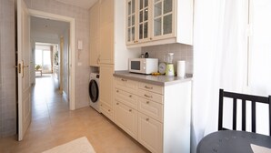 Een keuken met een wasmachine, magnetron en een klok op het aanrecht.